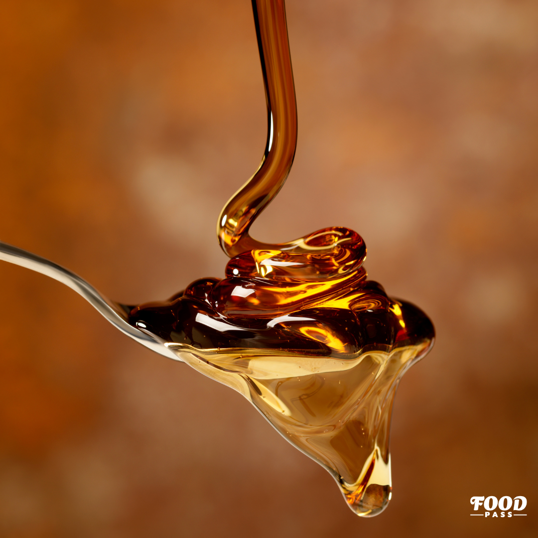 Sirop d’érable doré coulant lentement sur une cuillère, mettant en valeur la richesse et la texture onctueuse du produit. Une mise en avant de Sucrerie 66 Brix, vedette de la boîte FoodPass de février.