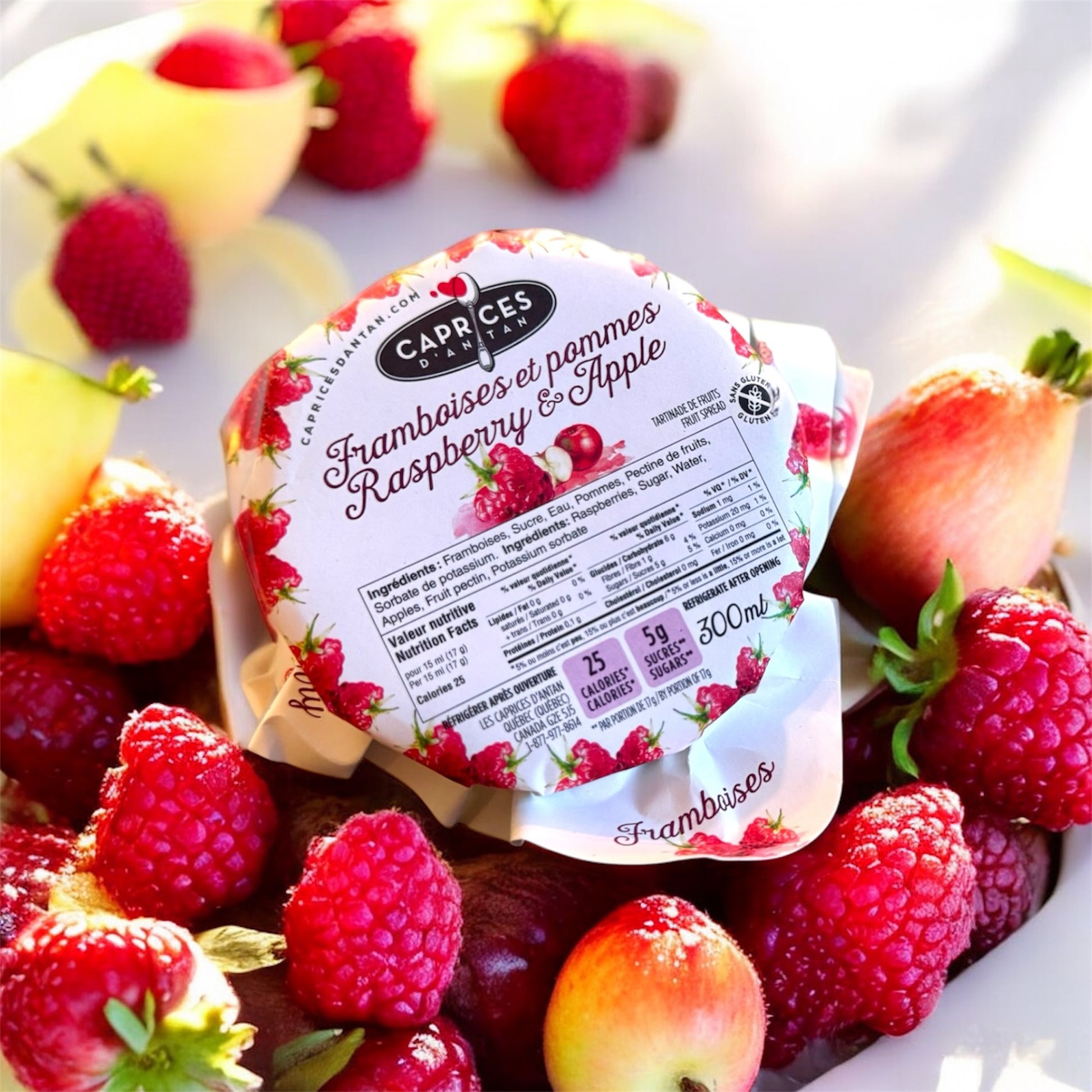 Tartinade artisanale Caprices d'Antan framboises et pommes sur une table en bois, entourée de fraises fraîches.